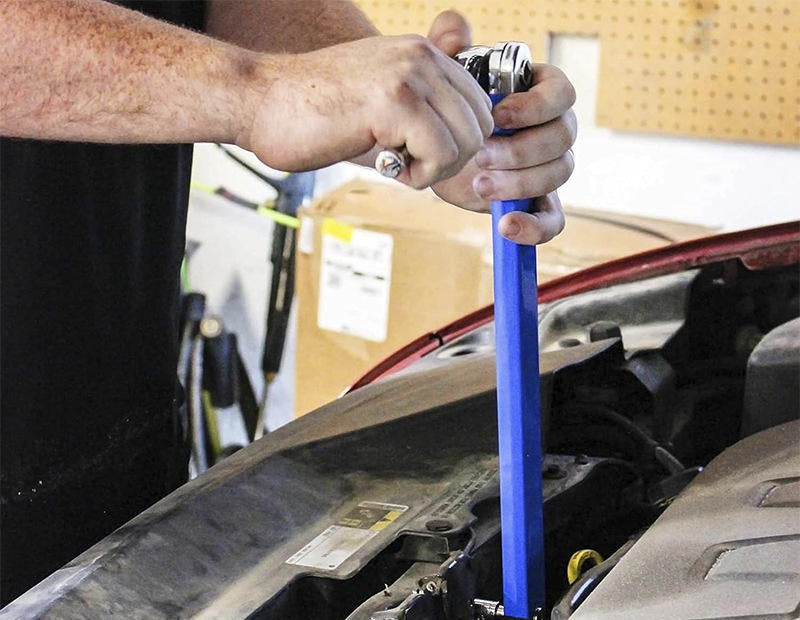 Rallonge déportée engagée sur un boulon au fond du compartiment moteur, le cliquet reste accessible à l'extérieur
